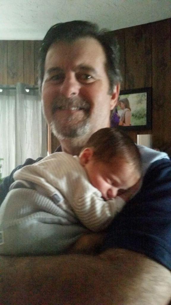 Proud GrandFather smiling and holding an infant